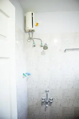 a white bathroom with a shower with a sink at Elite Dharshan H5 - AC 2 BHK Apartment near Guruvayur Temple in Guruvāyūr
