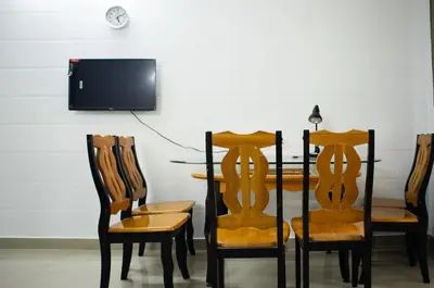 a dining room with a table and chairs and a tv at Elite Dharshan H5 - AC 2 BHK Apartment near Guruvayur Temple in Guruvāyūr