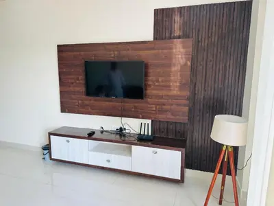 a living room with a television on a wall at Oryx Hotel Apartments in Mysore