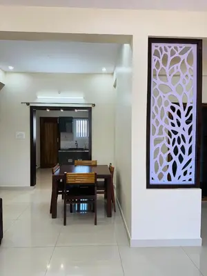 a dining room with a table and a white wall at Oryx Hotel Apartments in Mysore