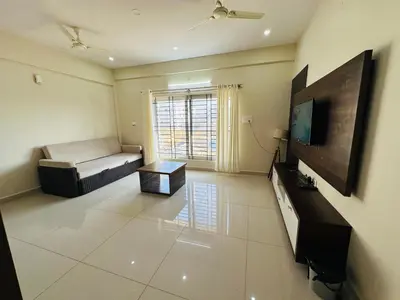 a living room with a bed and a flat screen tv at Oryx Hotel Apartments in Mysore