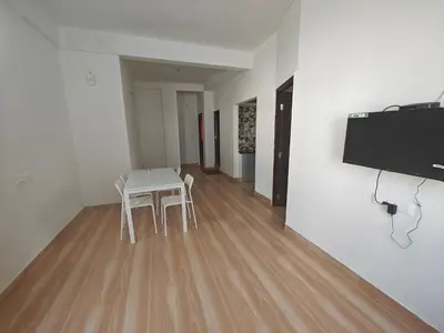 a room with a table and chairs and a flat screen tv at Downtown Service Apartments in Mysore