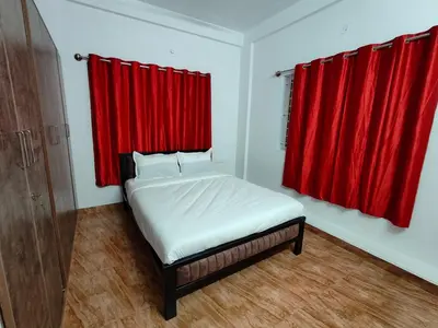 a bedroom with a bed with a red curtain at Downtown Service Apartments in Mysore