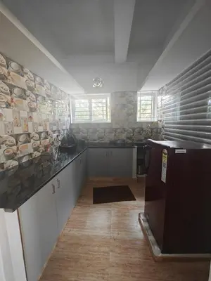 a kitchen with white cabinets and a counter top at Downtown Service Apartments in Mysore