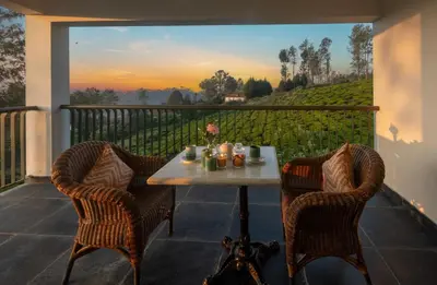 a table and chairs on a balcony with a view at Solitude by Nature Resorts and Stays in Kotagiri