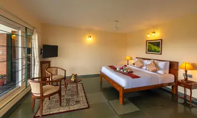 a bedroom with a bed and a table and a chair at Solitude by Nature Resorts and Stays in Kotagiri