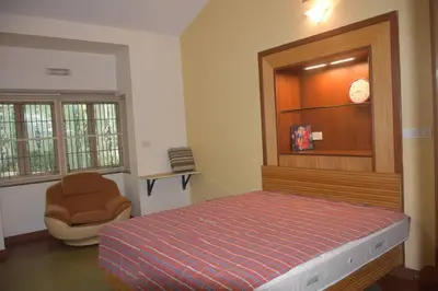 a bedroom with a bed and a chair in it at Golden castle in Mysore