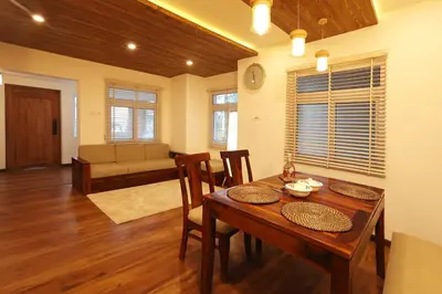 a dining room with a table and chairs and a couch at Green Wood Hill Cottage in Ooty