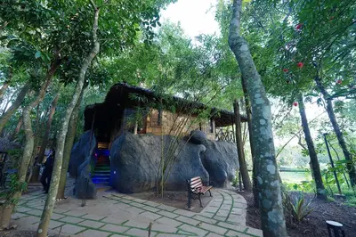 a bench sitting in front of a house in a forest at Mystery Maze Resort and Spa in Wayanad