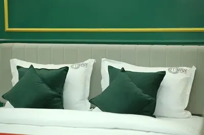 a white bed with four pillows and a green wall at Mystery Maze Resort and Spa in Wayanad