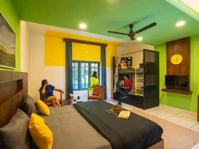 a bedroom with a bed and people in a room at The Hosteller Wayanad, Vythiri in Vythiri