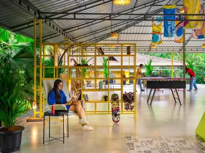 a woman sitting in a chair in a room with plants at The Hosteller Wayanad, Vythiri in Vythiri