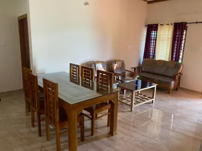 a living room with a table and chairs and a couch at HappyDays HomeStay Wayanad in Chekadi