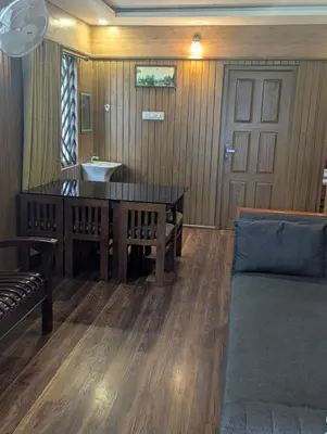 a living room with a table and a couch at Mountain Mist Meadows in Ooty
