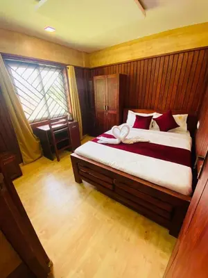 a bedroom with a large bed with red pillows at Mountain Mist Meadows in Ooty