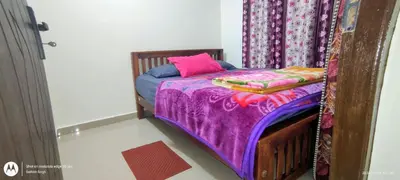 a bed with a purple blanket and a pink pillow at Hiya Holidays in Munnar