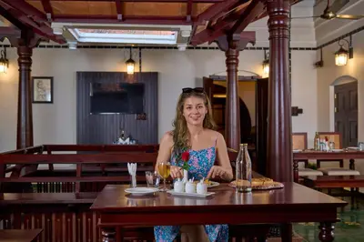 a woman sitting at a table in a restaurant at Malabar Kovilakam in Malappuram