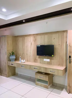 a living room with a tv on a wall at New Thai Residency in Dhārāpuram