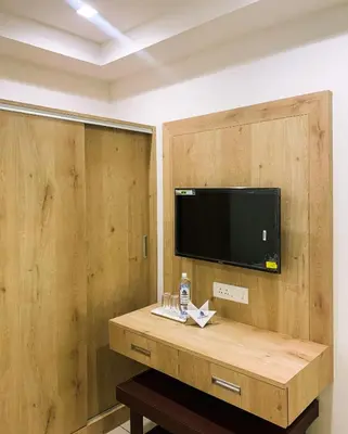 a room with a tv and a wooden wall at New Thai Residency in Dhārāpuram
