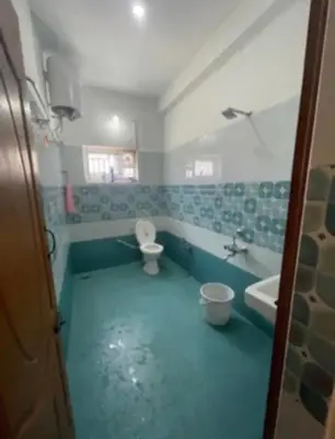 a bathroom with a blue floor and a toilet and a sink at White House Kotagiri, 2bhk in Kotagiri