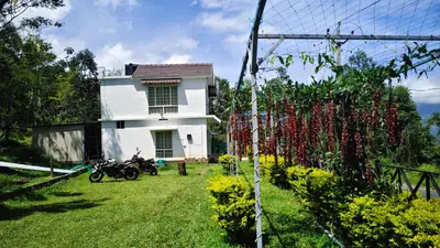 a white house with a fence with red flowers at LoveNest by ClubTravalet in Kanthalloor