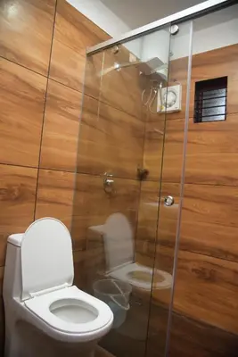 a bathroom with a toilet and a glass shower at TREE6 WAYANAD in Vythiri