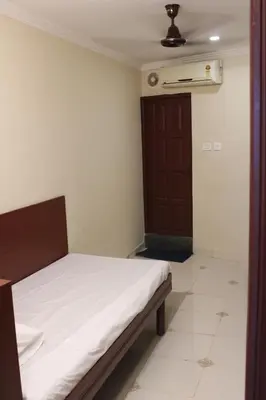 a bedroom with a bed and a brown door at LILLY RESIDENCY by Chungath in Perumbavoor