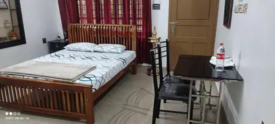 a bedroom with a bed and a table and a desk at Vyshnavi Home stay in Thanniyam