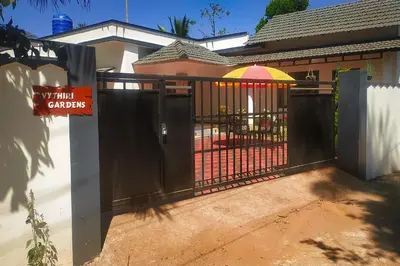a black fence with a gate with an umbrella at Vythiri Garden in Vythiri