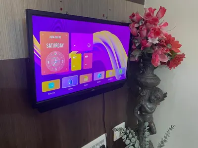 a television on a wall with a book on it at Spacious 2BHK for upto 12 Guests , Best for Families & Groups in Mysore