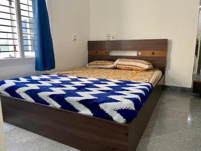 a bed with a blue and white comforter on it at Spacious 2BHK for upto 12 Guests , Best for Families & Groups in Mysore