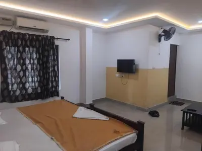 a room with a bed and a flat screen tv at Lotus Grand Residency in Angādipuram