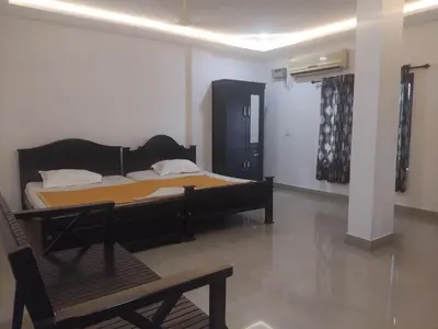 a bedroom with a bed and a table and a chair at Lotus Grand Residency in Angādipuram