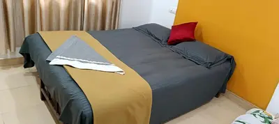 a bed in a room with a red pillow on it at JJ HOLIDAY HOMES WAYANAD in Kalpetta