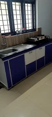 a kitchen with blue and white cabinets and a sink at JJ HOLIDAY HOMES WAYANAD in Kalpetta
