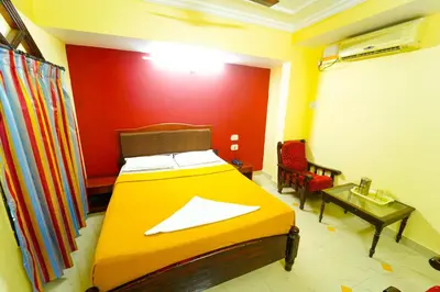 a bedroom with a bed and a chair and a table at AMOGHA RESIDENCY in Mysore