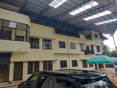 a car parked in front of a building with an umbrella at NEW MOUNT RESIDENCY in Sultan Bathery