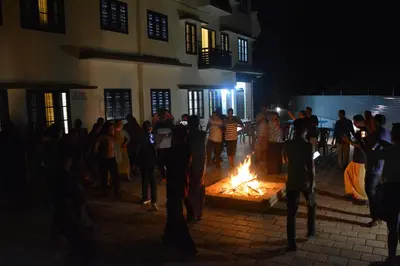 a group of people standing around a fire in front of a building at NEW MOUNT RESIDENCY in Sultan Bathery