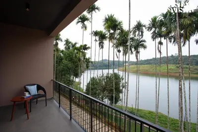 a room with a view of a river and palm trees at Rivera The Lake View with Indoor Games by StayVista in Wayanad