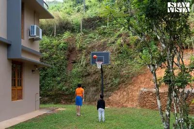 two people playing basketball in the yard of a house at Rivera The Lake View with Indoor Games by StayVista in Wayanad