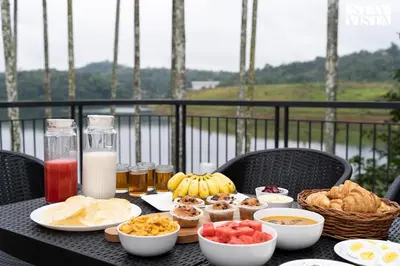a table with food and milk on a balcony at Rivera The Lake View with Indoor Games by StayVista in Wayanad