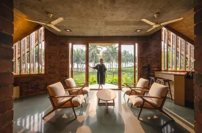 a woman is standing in a room with windows at Bimal's Casa de Papel in Kadikkād