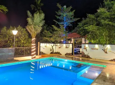 a swimming pool in a backyard at night at Wayanad Valentine Pool Resort in Sultan Bathery