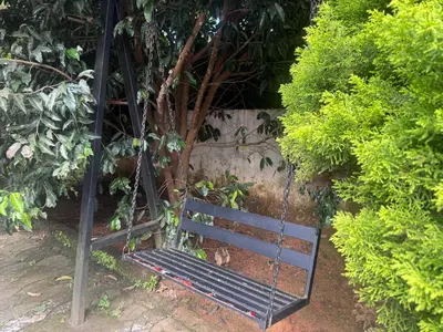 a swing in a garden with a tree at Empire Private Pool Villa in Kalpetta