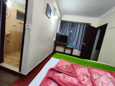 a bedroom with a bed and a bathroom with a shower at Munnar Kaippalli Budget Homestay in Munnar