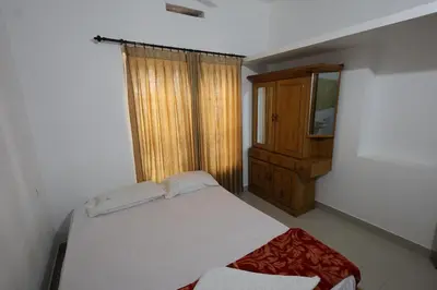 a bedroom with a white bed and a wooden cabinet at Wayanad regal residency in Kalpetta