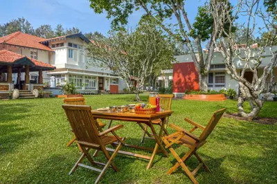 a wooden table and chairs in a yard at ama Stays & Trails Skanda , Coorg in Madikeri