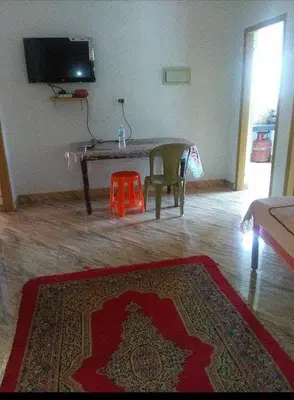 a living room with a table and a red rug at Anna homestay in Chekadi