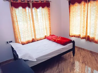 a small bed in a room with a window at Anna homestay in Chekadi