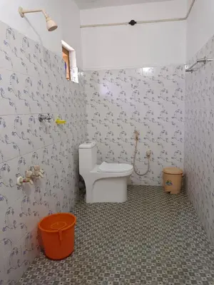 a bathroom with a toilet in a room with wallpaper at Anna homestay in Chekadi